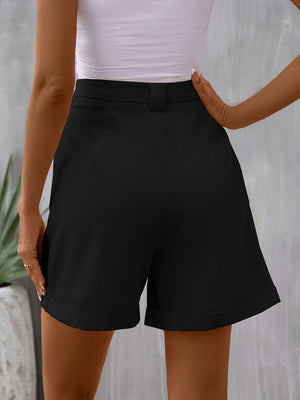 Black pleated bermuda shorts with cuffed hems and a cinched waist detail.