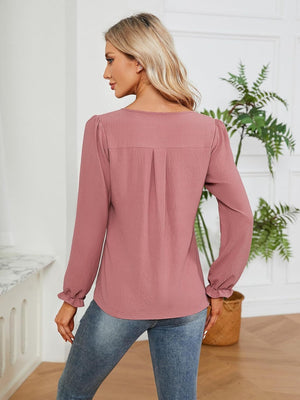Dusty pink textured pleat-front blouse with ruffle cuffs and long sleeves.