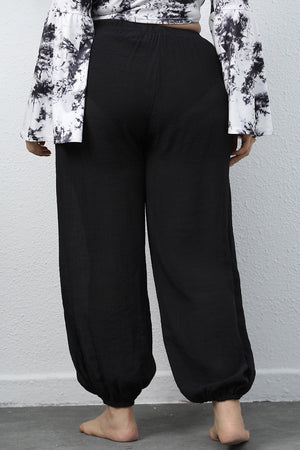 Black textured balloon-leg trousers with drawstring waist and elastic cuffs.