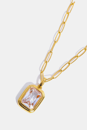 Gold paperclip chain necklace with a rectangular transparent crystal pendant.