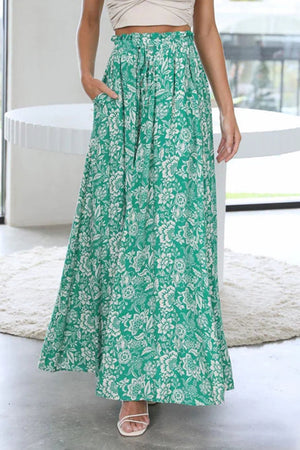 Botanical print palazzo trousers in green with white floral pattern, featuring pockets and a drawstring waist.