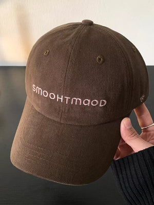 Dark brown cotton hat with pink embroidered text and small side detail.