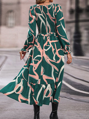 Midi dress in mid green with abstract print, smocked waist, long sleeves, and ruffled hem.
