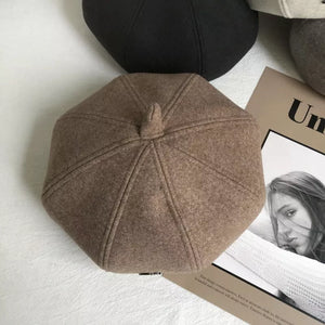 Woolen beret in beige with distinct paneled design and top button detail.