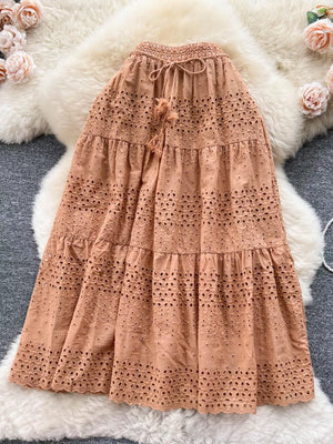 Light brown eyelet tiered maxi skirt with drawstring waist and tassel detail.