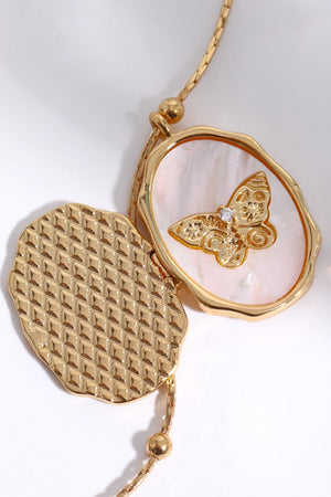 Gold locket necklace with mother of pearl inlay and a diamond-accented butterfly charm.