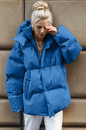 Oversized blue puffer jacket with hood and zip front, shown on a model.