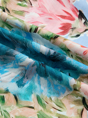 Women's cotton V-neck blouse with a vibrant abstract floral print in blue, pink, and green.