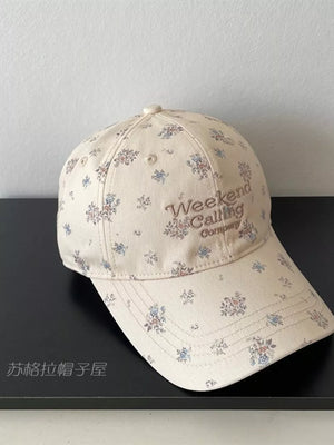 Ivory floral embroidered baseball cap with "Weekend Calling Company" text.