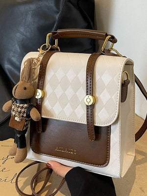 Mini quilted flap backpack bag in white and brown with gold hardware and bunny charm.