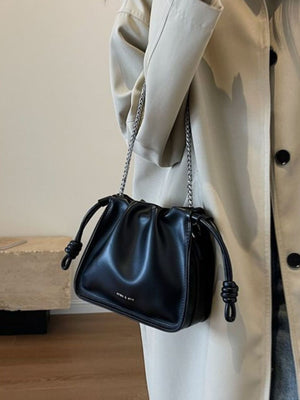 Black ruched PU leather crossbody bag with knotted strap details and silver chain.