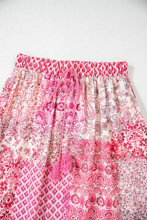 Printed tiered maxi skirt in dusty pink with tassel drawstring and boho patchwork pattern.