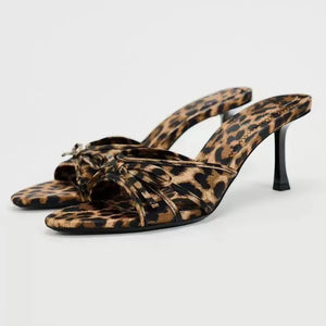 Leopard print knot heel mules with a pointed toe and stiletto heel.