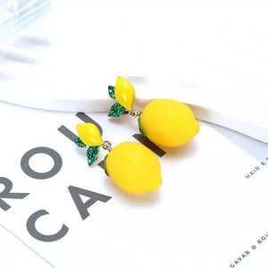 Gold-plated drop earrings with bright yellow lemon charms and green jeweled leaves.