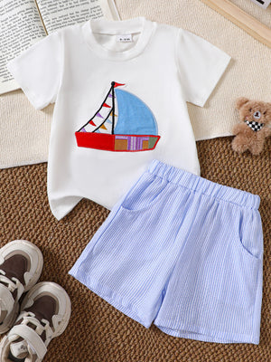 White baby tee with sailboat appliqué and blue striped shorts.