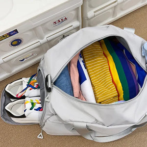 Light Gray duffel bag packed with clothes and white sneakers with rainbow laces.