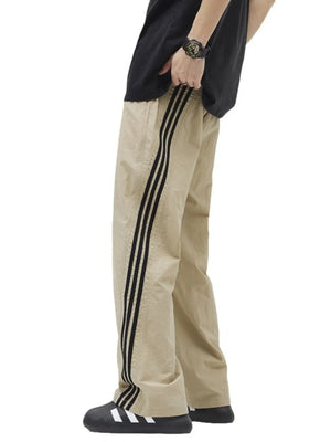 Khaki drawstring pants with black side stripes and perforated detail.