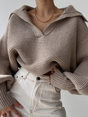 Tan knit sweater with wide collar and balloon sleeves, styled with white jeans.