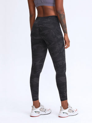 Black camouflage print performance leggings with pockets and reflective ankle detail.