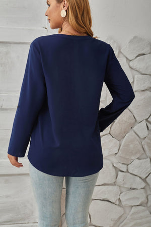 Dark blue V-neck blouse with cuffed long sleeves and button detail.