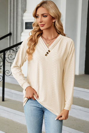Cream textured henley v-neck top with button detail and long sleeves.