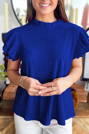 Blue textured short sleeve shirt with ruffle trim and mock neckline.
