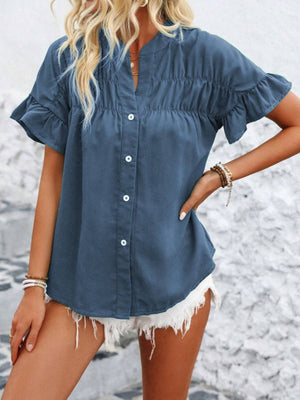 Dusty blue button-up blouse with gathered yoke and ruffle sleeves.