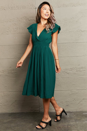 Emerald green pleated flutter sleeve dress with V-neck and cinched waist