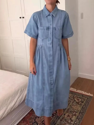 Denim midi dress with short sleeves, collared neckline, button front, and chest pockets.