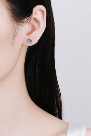 Silver moissanite stud earrings with a sculpted setting on a woman's ear.