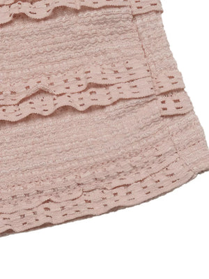 Pink textured romper with tiered ruffles and cut-out details.