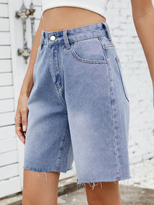 Longline denim cutoff shorts in medium wash with a raw hem.