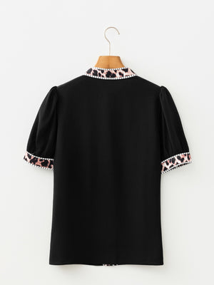 Black puff sleeve blouse with leopard print trim on collar and cuffs.