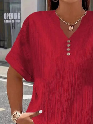 Red textured v-neck t-shirt with decorative buttons and short sleeves.