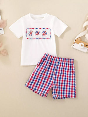 White smocked tee with fireworks detail and red, white, blue plaid shorts set.