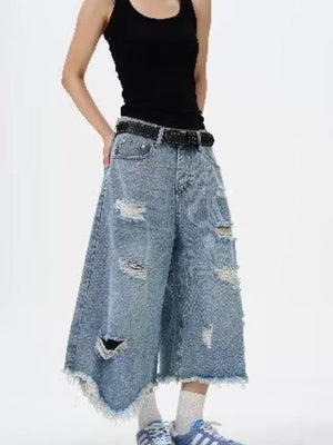 Distressed light wash denim wide-leg jeans with raw hem and ripped details.