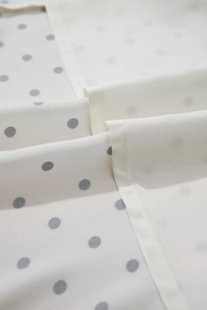 White polka dot midi dress fabric detail with tie belt visible