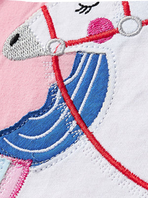 Baby t-shirt with pink and white unicorn applique, blue mane, and red bridle detail.