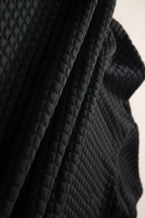 Black quilted knit fabric detail on a crop top and jogger set.