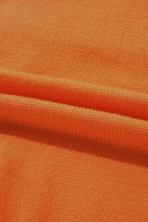 Orange knit sweater fabric detail with textured weave and soft folds.