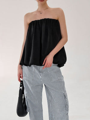 Black strapless bubble hem top with a ruffled neckline, worn with striped pants.