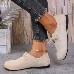 Beige matte fabric round toe flats with cord detail and buckle accent.
