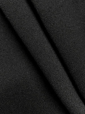Black knit fabric detail of a drape-front blazer with sculpted silhouette.