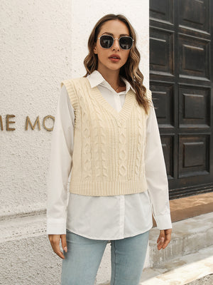 Ivory cable knit crop vest sweater with V-neck and ribbed trim, styled over a white button-down shirt.