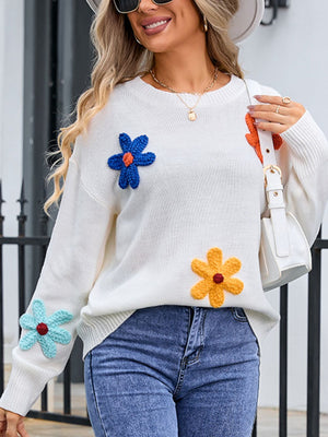 White knit sweater with embroidered flower appliqués in blue, orange, yellow, and teal.