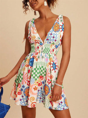 Playful printed mini dress with tied straps, V-neck, smocked waist, and colorful sun and checkered patterns.