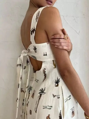 Sleeveless maxi dress in white with vacation-themed print, tie-back detail, and pockets.