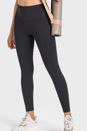 Black seamless high-waist performance leggings with a yoga mat slung over the shoulder.