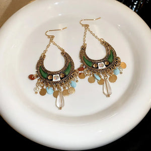 Bohemian crescent drop earrings in dark green with gold alloy, beads, and charms.