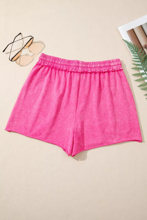 Hot pink acid-washed cotton drawstring shorts with elastic waist and raw hem.